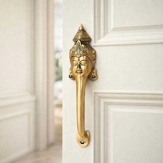 Decorative Goddess face brass door handle with intricate design on a white door.