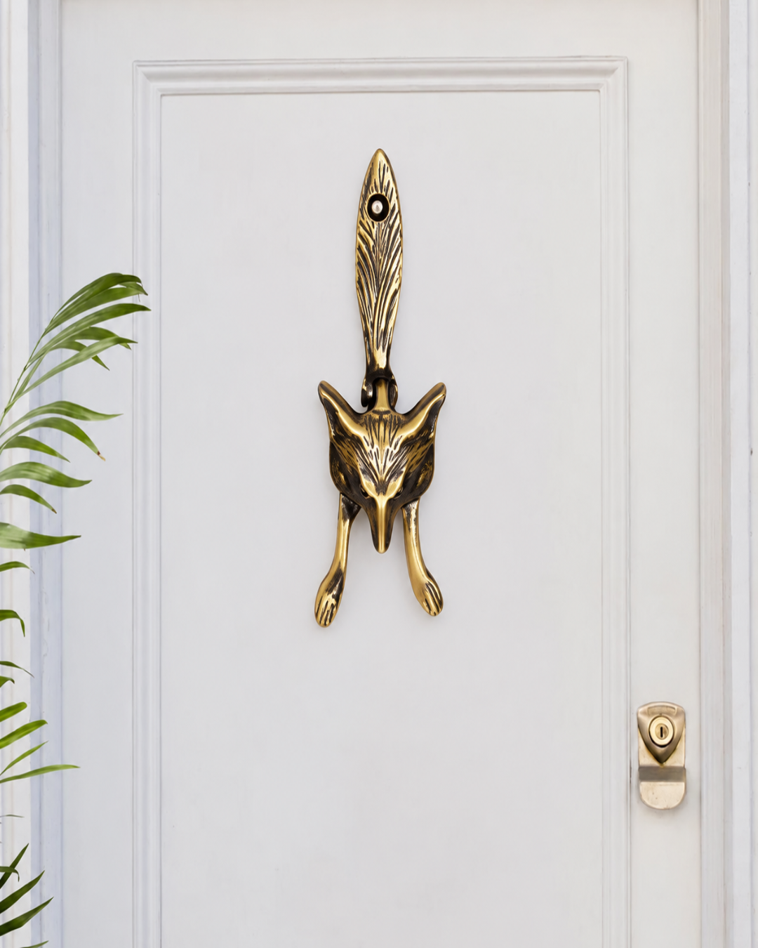 A premium brass door knocker shaped like a fox head with a feather detail on a white wooden door