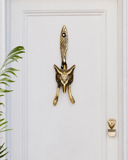 A premium brass door knocker shaped like a fox head with a feather detail on a white wooden door