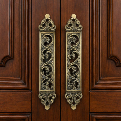 Decorative Brass door pull handles on a wooden door.