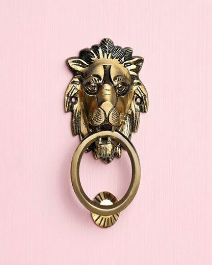 Brass lion head door knocker on a pink background