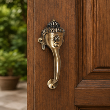 Brass door handle shaped like a Buddha head on a wooden door.