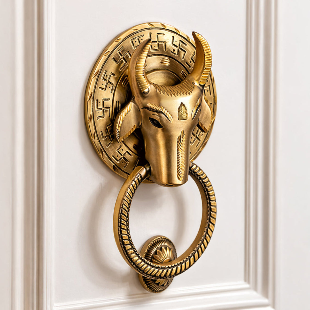 Decorative gold door knocker with bull head design on a white paneled door