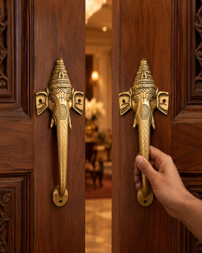 Decorative brass door handle shaped like an elephant on a wooden door, with a hand about to open it.