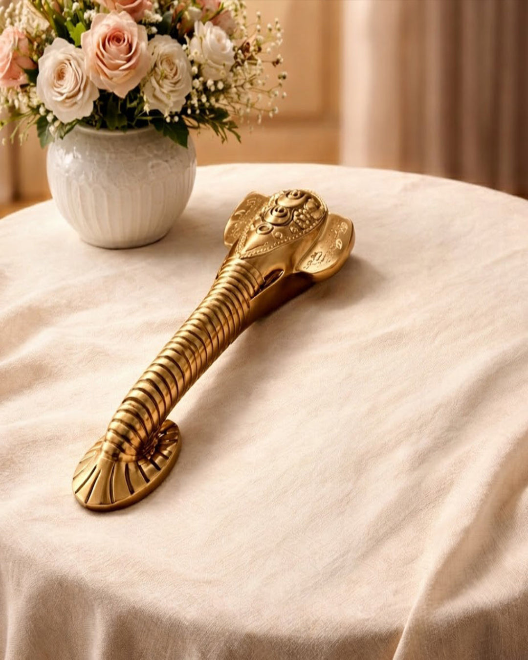 Decorative gold object on a table with flowers in the background