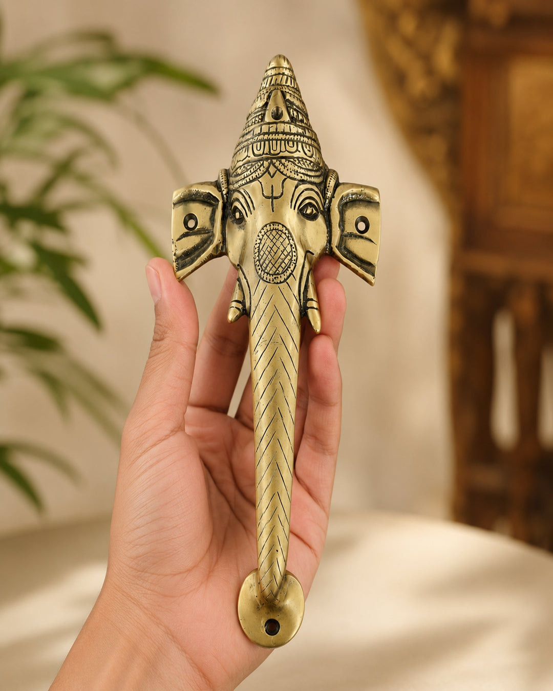 Hand holding a decorative brass door handle with Traditional design.