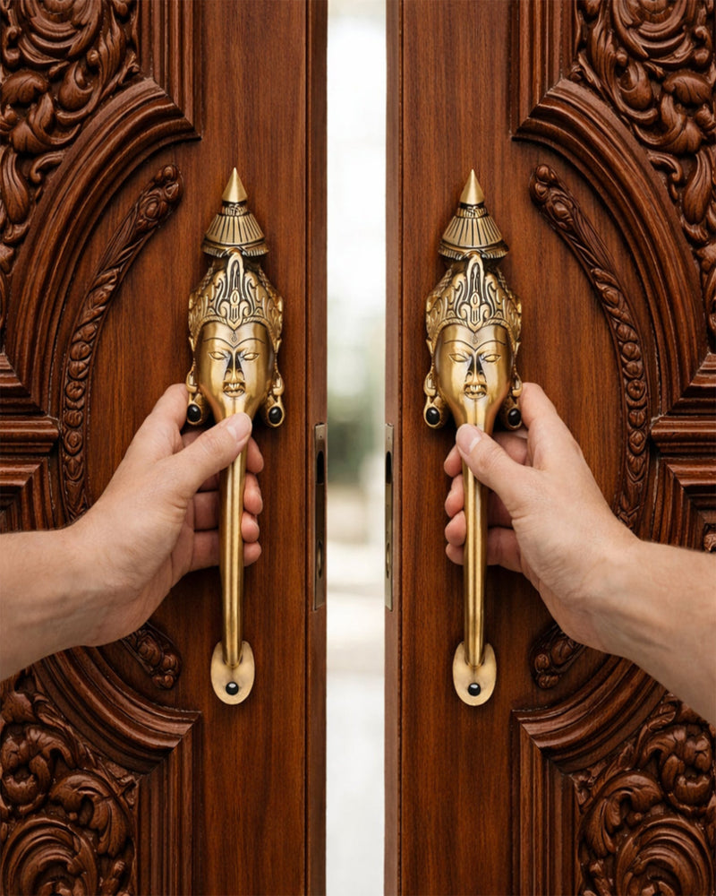 Two hands opening a wooden door with ornate carvings and gold handles featuring facial designs.
