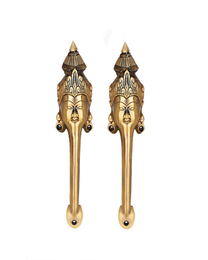 Pair of brass door handles with face designs on a white background.