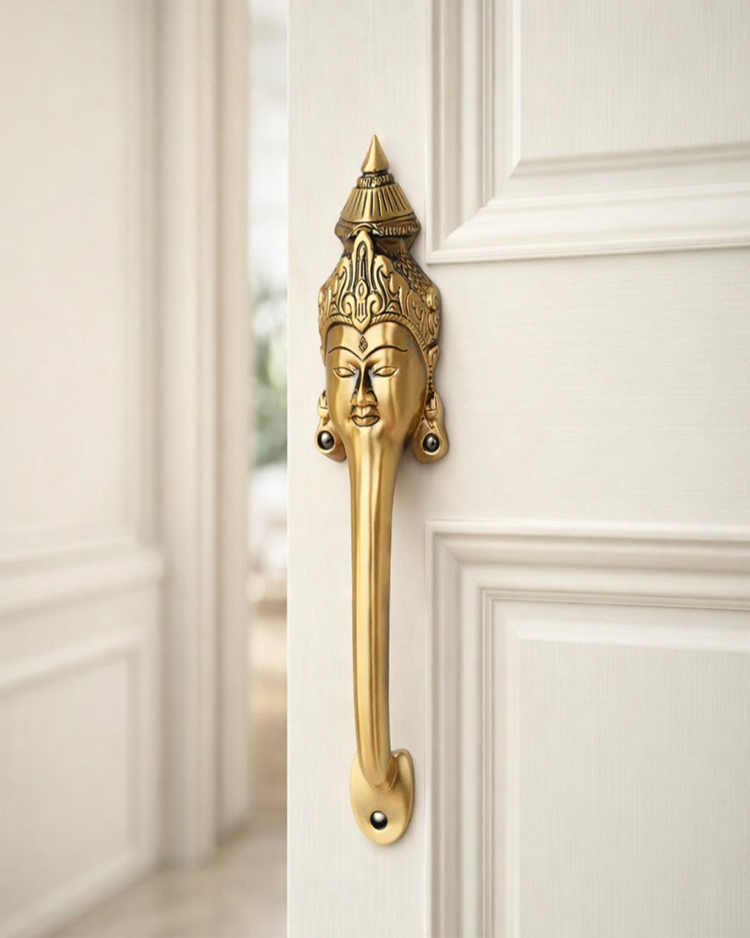 Decorative Goddess face brass door handle with intricate design on a white door.