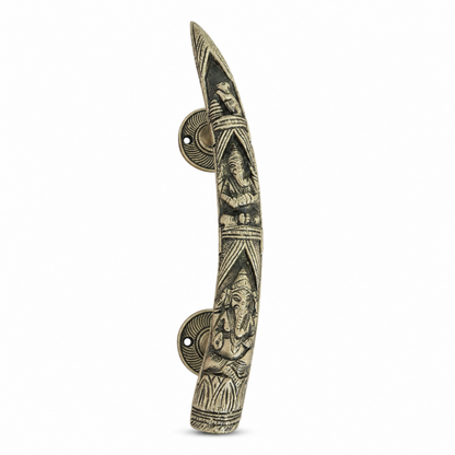 An ornate, curved brass door pull handle featuring detailed carvings of Lord Ganesha and a traditional Indian architectural motif, set against a plain white background.