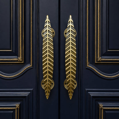Two gold leaf-shaped door handles mounted on dark navy blue paneled doors with gold trim.