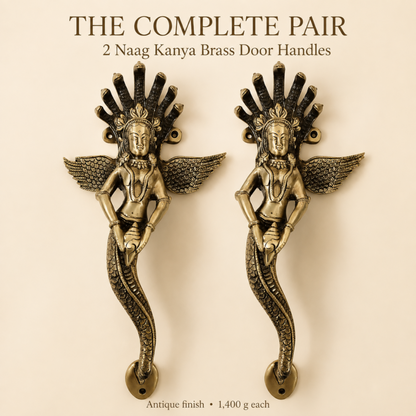 A pair of antique brass door handles shaped like dancing winged female figures with a serpent-like lower body, shown on a beige background with text reading 'THE COMPLETE PAIR 2 Naag Kanya Brass Door Handles' and 'Antique finish 1,400 g each'.