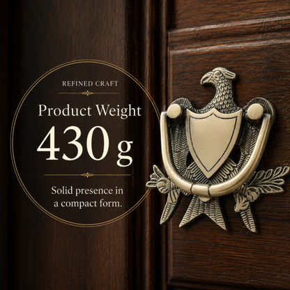 An antique-style eagle door knocker in a brushed brass/gold finish mounted on a dark brown wooden door. A circular text overlay on the left reads 'REFINED CRAFT Product Weight 430 g Solid presence in a compact form.