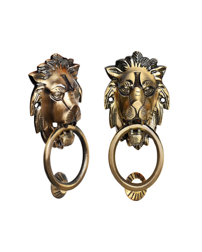 Two brass lion head door knockers on a white background